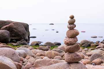 Pyramid of granite stones or rocks on the coast of the sea, ocean or on the beach of the lake or river in the summer or autumn sunny day. Vivid, bright and colorful marine landscape or view