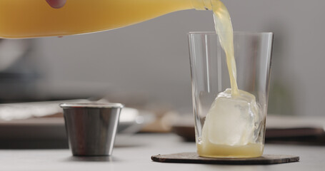 man pour orange lemonade in tumbler glass with ice
