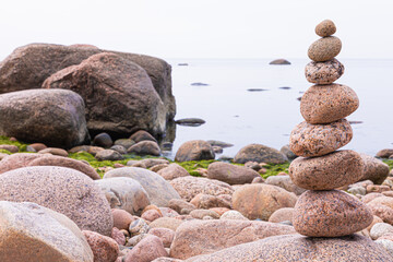 Pyramid of granite stones or rocks on the coast of the sea, ocean or on the beach of the lake or...
