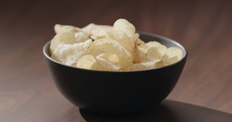 potato chips in black bowl on walnut table