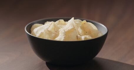 potato chips in black bowl on walnut table