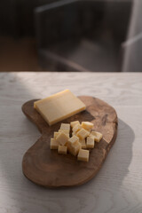 Small block of aged cheese sliced in small pieces on wood board