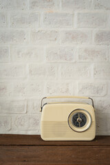 Antique beige color radio on the wooden shelves decoration and brick wall interior classic home and living retro building.