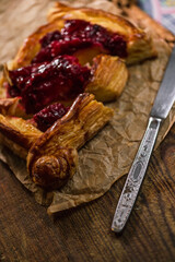 Homemade puff pastry with cherry on old black cooking sheet. Sweet tasty dessert. 