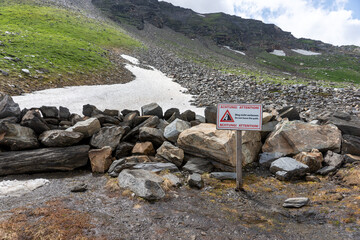 Warning sign rockfall with text - Attention! Do not leave the path - english and german language