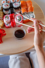 Girl eating sushi roll california holding bamboo sticks in her hand