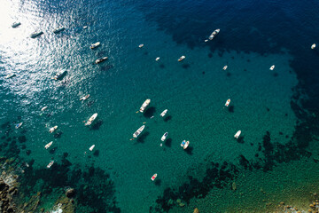 Fototapeta na wymiar View from above, stunning aerial view of a bay with boats and luxury yachts sailing on a turquoise, clear water. Porto Santo Stefano, Italy.