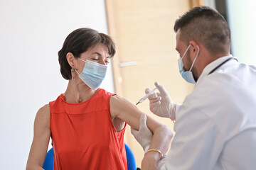 Injection of the vaccine against the covid-19 by a doctor  in a vaccination center