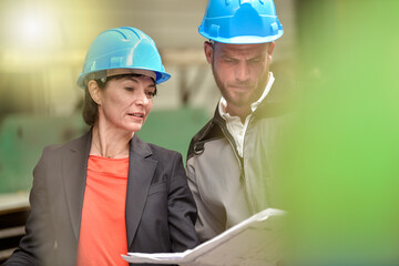 Confident female engineer is giving instruction and showing  blueprint to a male worker