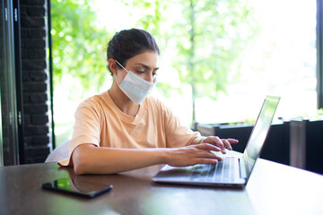 Indian business woman working on her laptop outdoor with mobile phone and face mask