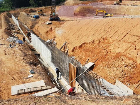 PENANG, MALAYSIA -MARCH 5, 2021: Reinforce Concrete retaining wall construction is in progress. Workers fabricated the timber formwork before pouring the concrete inside it. 