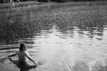 Caucasian woman back in white shirt in pond. Monochrome