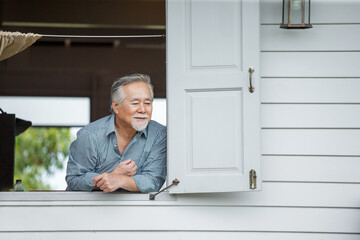 happy asian senior man in window at home