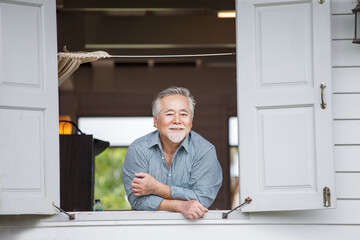 happy asian senior man in window at home