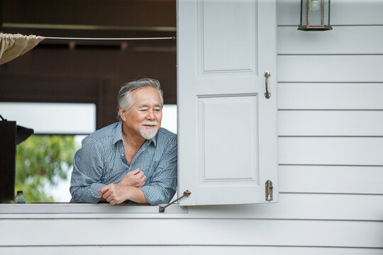 happy asian senior man in window at home