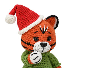 Knitted tiger in a green sweater and santa hat