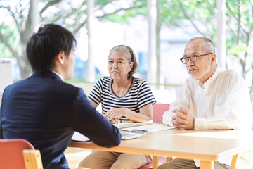 高齢者夫婦に介護施設のアドバイスをするビジネスマン