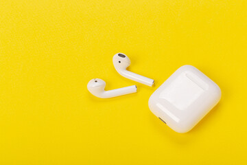 wireless bluetooth headphones with charging case on a yellow background. The concept of modern...