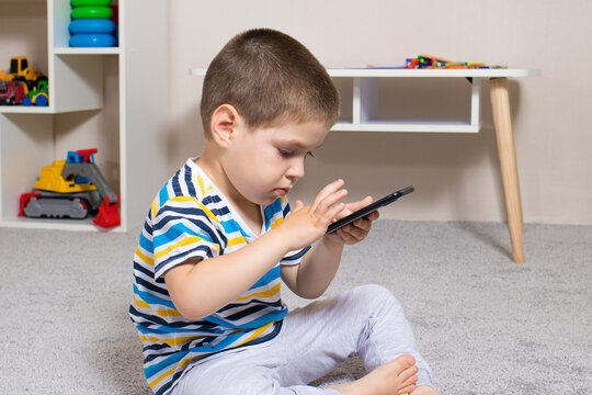 A small child and a mobile phone in the children's room with place for text. Cartoons and dependence on gadgets in children, limiting children from adult content on the Internet