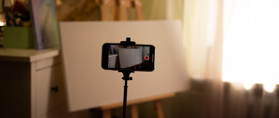 Shooting a video tutorial on drawing a picture on canvas with an easel at home. Wide photo