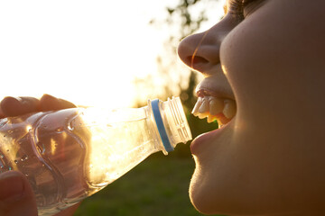 cheerful woman drinking water from a bottle and close-up nature summer