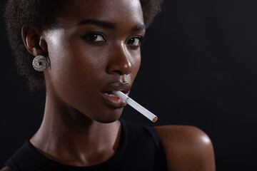 Sexy african american woman smoking cigarette on black dark background. - Powered by Adobe