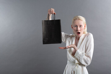 White caucasian albino blond woman holds shopping bag. Sale and discounts on market and Black...