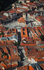Fototapeta na wymiar Elevated street view of medieval city of Brasov Romania overlooking red rooftops and fortified walls of citadel