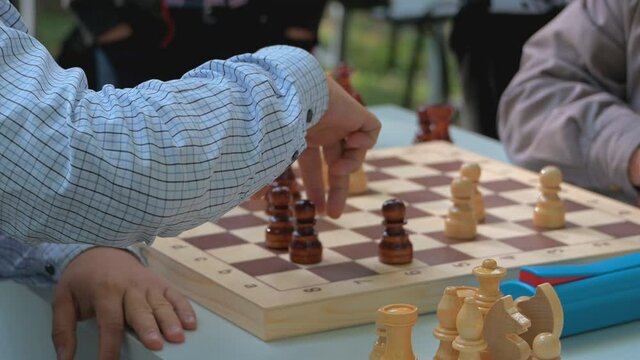two men play fast chess at a blitz tournament among the elderly, a chess match in nature, outdoors, selective focus