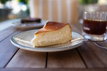 Fototapeta premium Cheescake San Sebastian slice on dish at cafe table.