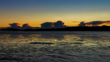 A golden sunset reflecting over the mudflats of Kirkcudbright Bay in winter