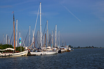 Fototapeta na wymiar Sea bay with yachts. Sailboats on water, blue seawater, clear sky. Harbor of Monnickendam, the Netherlands. 