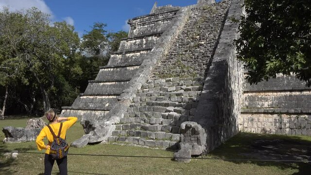 Mature blond woman walks among the ruins at Chichen Itza historical park in Yucatan, Mexico.