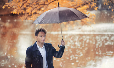 Autumn rainy weather and a young man with an umbrella