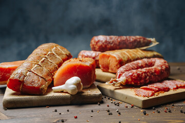 Various types of meat and sausages on wooden table, served on board, closeup