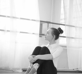 Young ballet dancer on a warm-up. The ballerina is preparing to perform in the studio. A girl in ballet clothes and shoes kneads by the handrails.