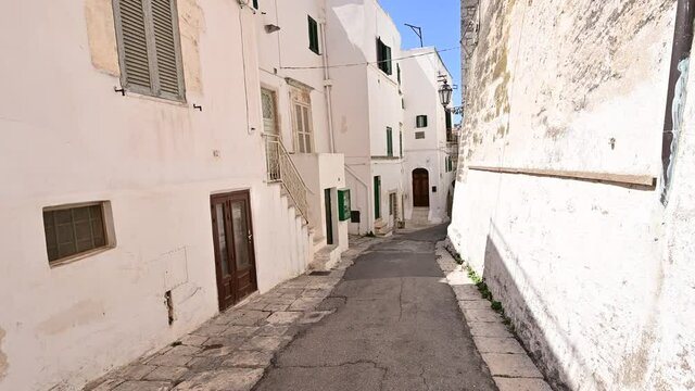 Ostuni, Puglia, Italy. August 2021. POV footage strolling through the white alleys of the historic center: enchanting glimpses full of charm, you advance along the pavement.