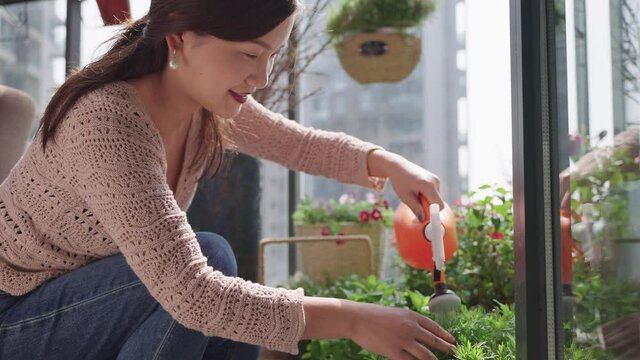 4k close up side view of beautiful Chinese women happily watering flowers on her balcony The Home Lifestyle of Urban People