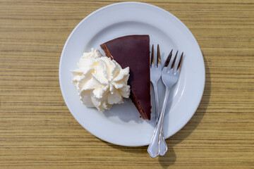 Top view of Original Sacher-Torte on table served with whipping cream, The cake consists of a dense...