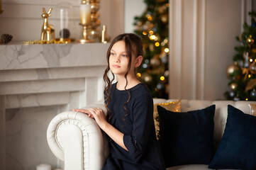 Young girl with dark hair in a Christmas interior in white and gold colors.