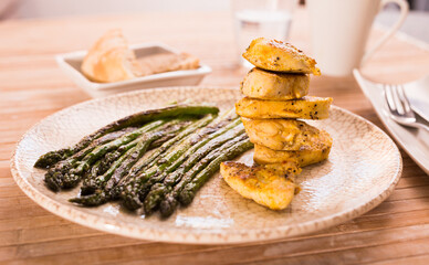 fried chicken breast pieces with asparagus on white plate