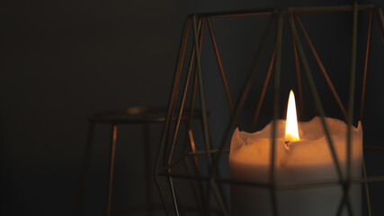 candle in dark room in gold candlestick, warm fire light in darkness