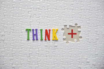 THINK word on the white puzzle with POSITIVE symbol on the blank missed puzzle. Lifestyle concept.