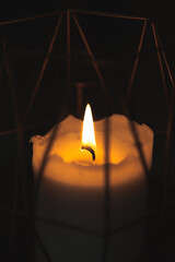 candle in dark room in gold candlestick, warm fire light in darkness, closeup