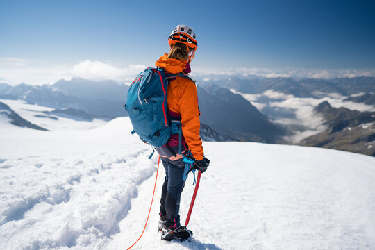 Woman of mountaineer climb a snowy peak. In background the glaciers and the summit of Mont Blanc, the highest european mountain. Chamonix, France, Europe.
