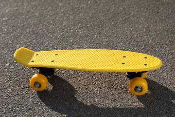 Stylish yellow skate board on asphalt outdoors