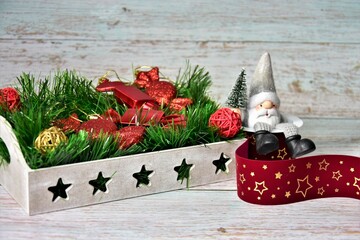 christmas tree decorations in a wooden tray, santa claus and red velvet ribbon 