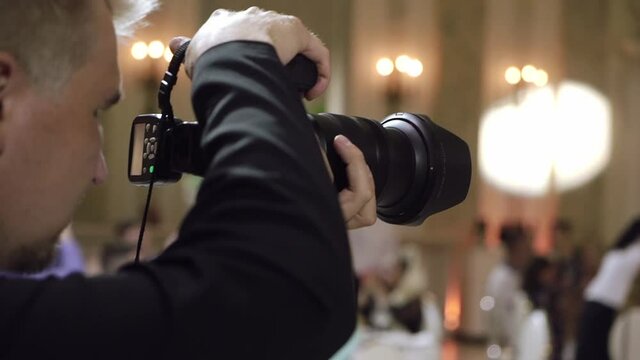 Man photographer takes pictures in a restaurant, party at wedding event.