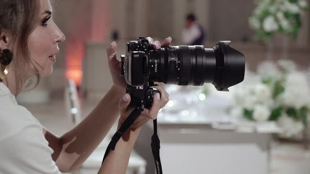 Girl photographer takes pictures in a restaurant, banquet hall at wedding event.