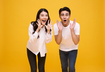 Young Asian couple man and woman happy and shout announce on yellow background..